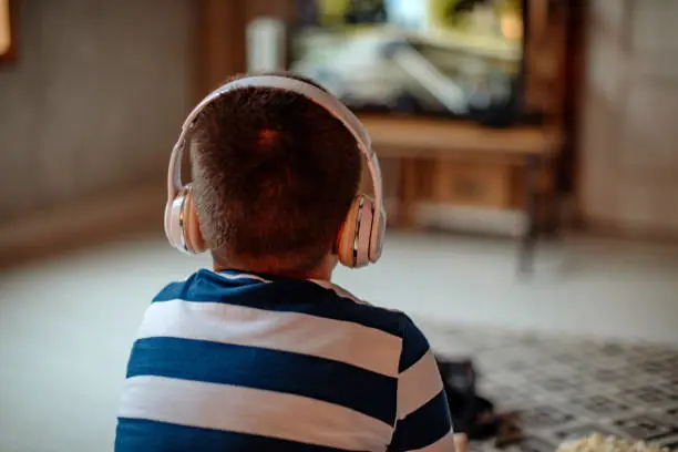 Gambar seseorang menonton TV dengan headphone